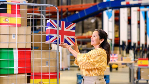 Webshopondernemer legt een internationaal pakket in een rolcontainer vol met internationale pakketten