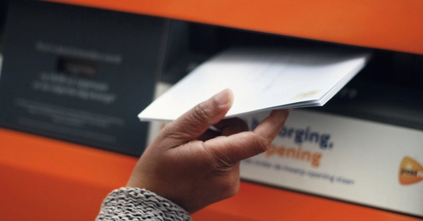 closeup van een brief die in een brievenbus wordt gedaan