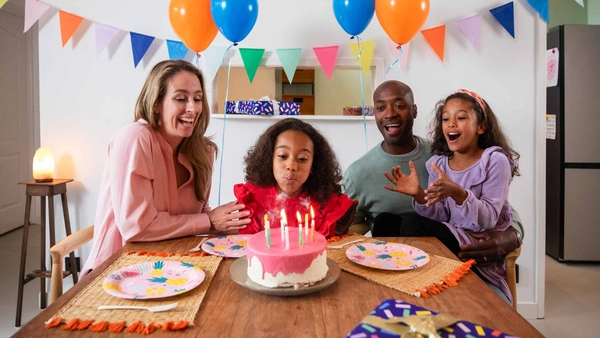 Vader, moeder en twee dochters vieren vrolijk de verjaardag van een van de dochters met een taart met kaarsjes
