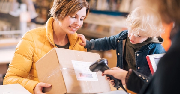moeder en zoontje laten een pakket scannen bij een pakketpunt