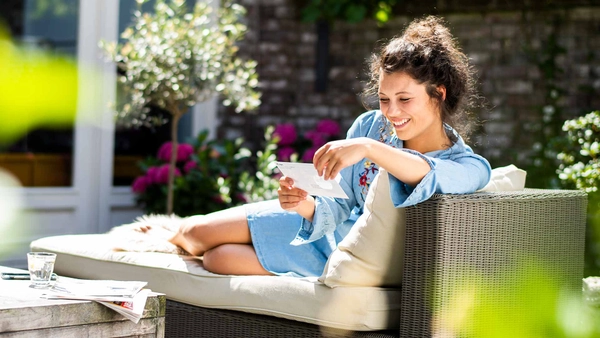 Vrouw leest een brief terwijl ze in een ligstoel in de tuin zit
