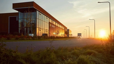 Een kantoorpand van buitenaf, met een vrachtwagen die langsrijdt