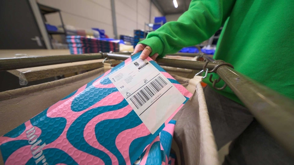 Brievenbuspakje met internationaal verzendlabel rolt over de rolband in het magazijn van een webshop