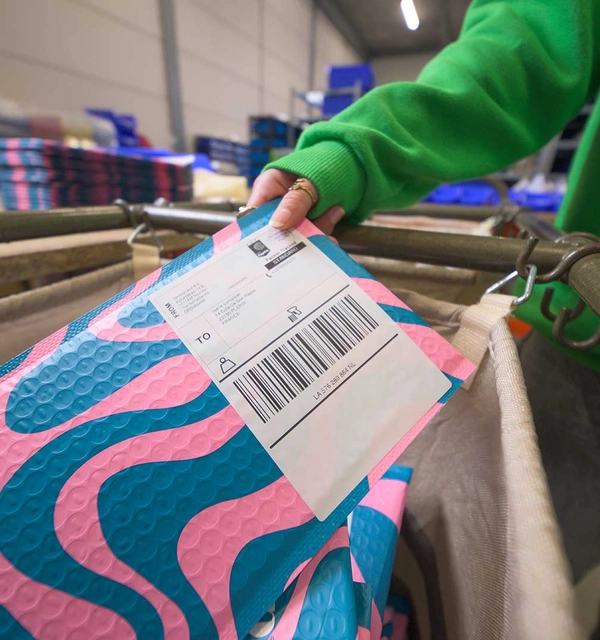 Brievenbuspakje met internationaal verzendlabel rolt over de rolband in het magazijn van een webshop