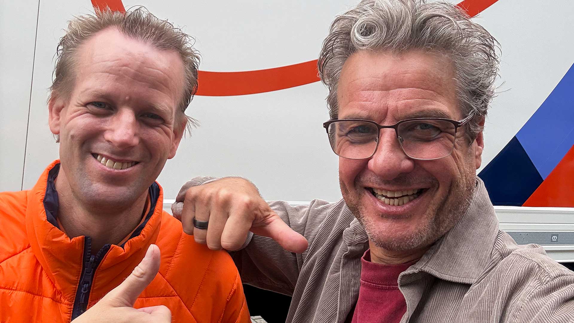 Maurice en PostNL-chauffeur poseren voor een PostNL-vrachtwagen, waarvan één een duim omhoog houdt.