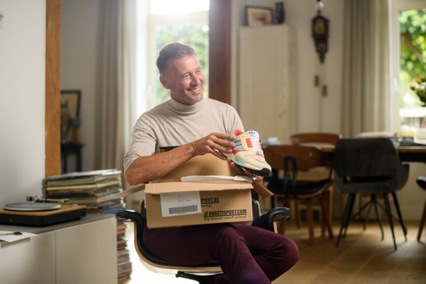 Blije man opent een pakket met nieuwe schoenen