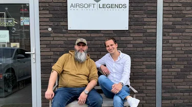 Twee mannen zitten op een bank voor het pand van Airsoft Legends