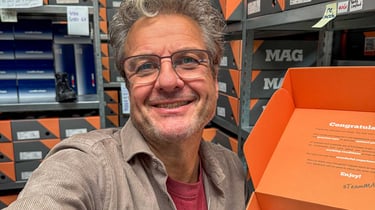 Maurice van MAG houdt in een webshop magazijn een open schoenendoos vast.