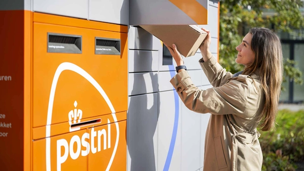 Vrouw haalt een pakket uit een PostNL-pakketautomaat