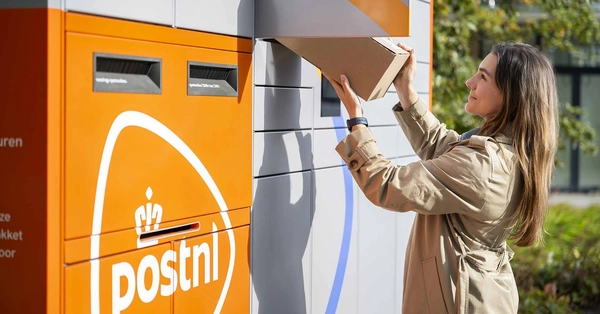 Vrouw haalt een pakket uit een PostNL-pakketautomaat