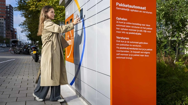 Vrouw opent een pakketautomaat met haar PostNL-ID op haar telefoon