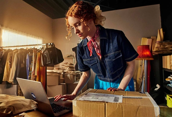 Webshopmedewerker pakt een retourpakket uit en verwerkt dit in een computer