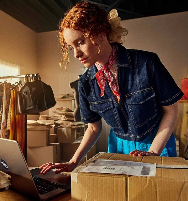 Webshopmedewerker pakt een retourpakket uit en verwerkt dit in een computer