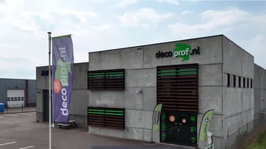 Pand van Decoprof met bedrijfslogo en vlag bij de ingang.