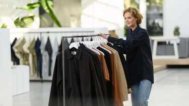 Medewerker duwt een rek vol kleding door een showroom