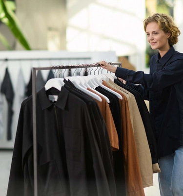 Medewerker duwt een rek vol kleding door een showroom