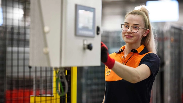 Vrouw in PostNL-kleding bedient een machine in een sorteercentrum