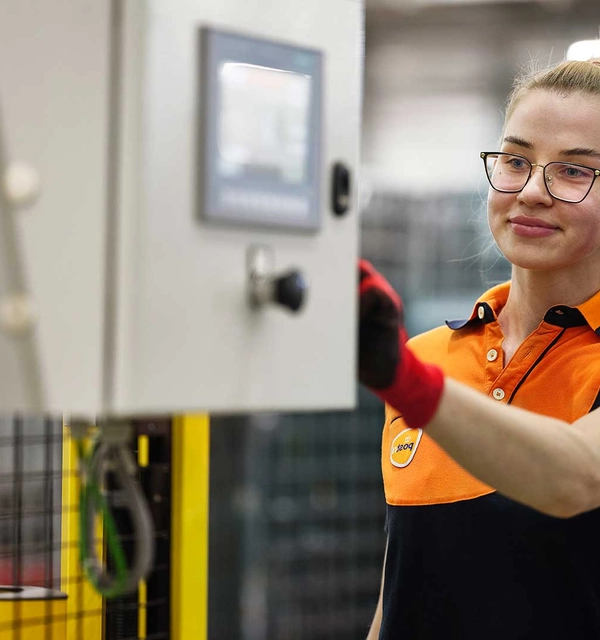 Vrouw in PostNL-kleding bedient een machine in een sorteercentrum