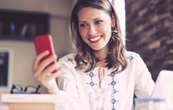 Vrouw kijkt lachend naar haar mobiele telefoon