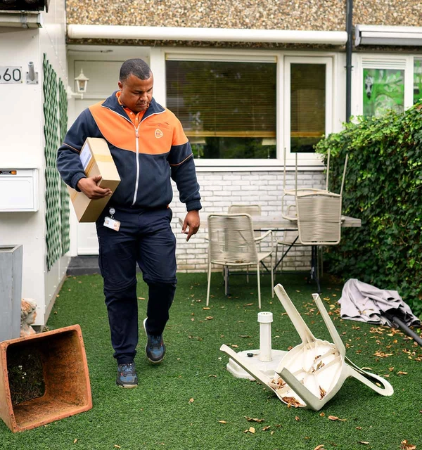 Pakketbezorger loopt door een tuin vol rommel.