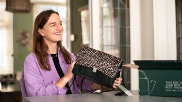 Consument pakt  een tasje uit een pakket en kijkt daarbij heel tevreden