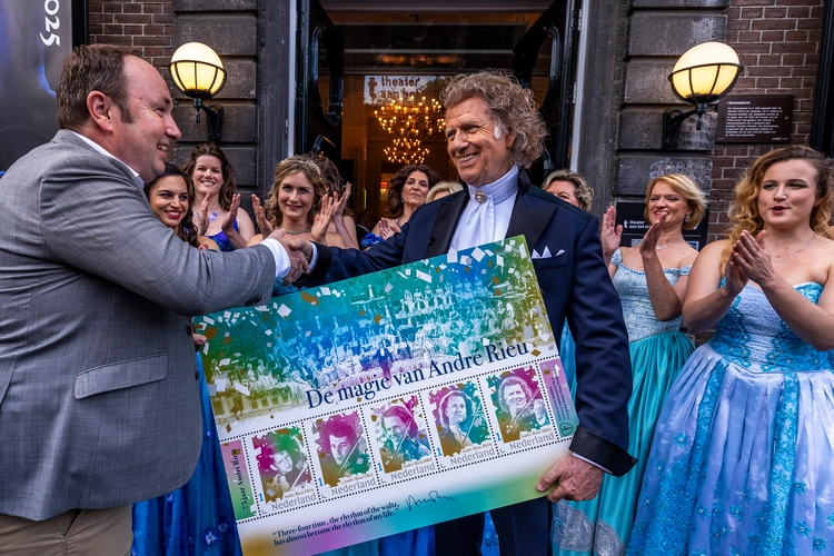 PostNL directeur overhandigt André Rieu een uitvergroot exemplaar van het kleurrijke postzegelvel