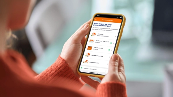 Consument houdt een telefoon vast met daarop een keuzescherm met bezorgvoorkeuren